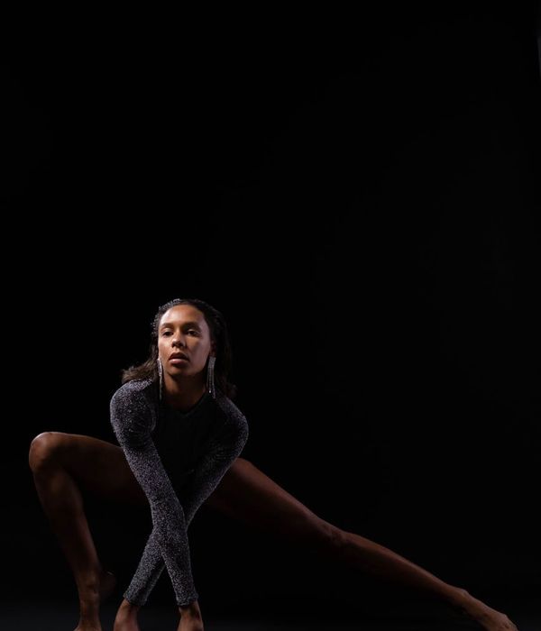 Woman in a dynamic morning yoga pose against a dark background.